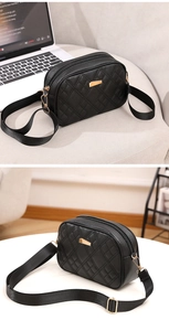 Detail of black quilted shoulder bag with dual zipper compartments and wide strap