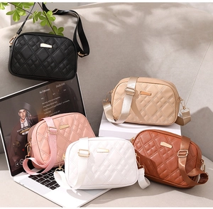 Detail of quilted crossbody bags in multiple colors with wide fabric straps and gold hardware