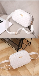 Close-up of white quilted crossbody camera bag with gold metal hardware and fabric strap