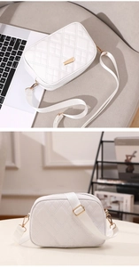 Detail of white quilted crossbody bag featuring a wide fabric strap and golden metal buckle