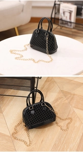 Close-up of black shell-shaped jelly bag with spherical rivets and gold chain strap