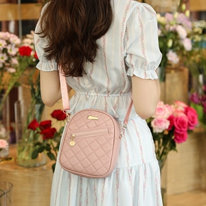 Pink quilted PU leather crossbody bag with adjustable strap worn in a floral studio