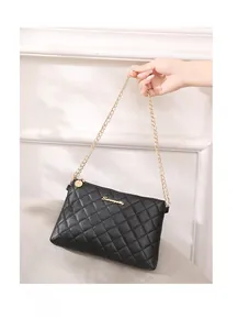 Détail du sac à bandoulière noir matelassé avec chaîne dorée et plaque logo en métal