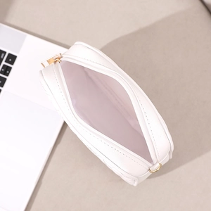 White quilted crossbody phone bag with gold hardware and interior view on desk