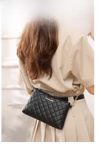 Détail d'un sac à bandoulière noir matelassé avec chaîne dorée porté par un mannequin