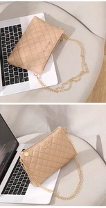 Gros plan d'un sac bandoulière matelassé beige avec chaîne dorée et logo en métal