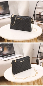 Détail du sac bandoulière noir matelassé avec chaîne dorée sur surface en marbre blanc