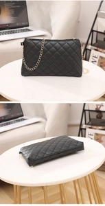 Détails d'un sac noir matelassé avec chaîne dorée posé sur une table en marbre élégante