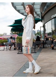Foto lifestyle di una borsa a secchiello intrecciata colorata con manici bianchi