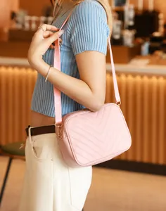 Bolso bandolera rosa de piel sintética con acolchado en V mostrado por una modelo
