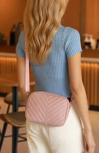 Detalle del bolso de cámara rosa con acolchado en V y cremallera dorada elegante