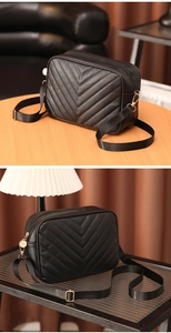 Detalle de bolso negro con acolchado en V y cremalleras de metal dorado elegantes