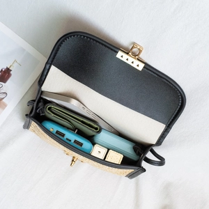Bolso bandolera de paja para mujer con solapa de cuero negro que muestra capacidad interna