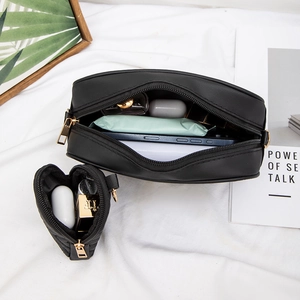 Chic black camera bag set with gold zippers and matching heart-shaped charm on white fabric