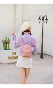 Pink quilted backpack with butterfly charm shown on a model in an outdoor setting