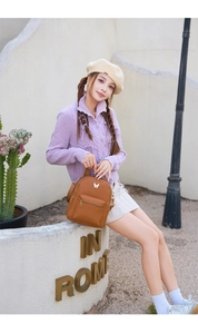 Outdoor shot of a woman wearing a brown quilted backpack with a white butterfly ornament