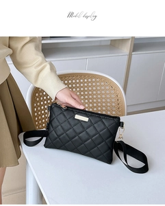 Quilted black crossbody bag with gold hardware detail and adjustable strap on a chair