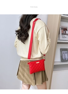 Detail of red quilted crossbody bag with adjustable wide strap shown on a model