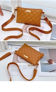 Detail of a brown quilted crossbody bag with gold zipper and adjustable wide strap