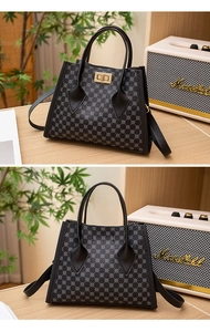 Detail view of black cross-body bag with geometric pattern and golden twist-lock closure