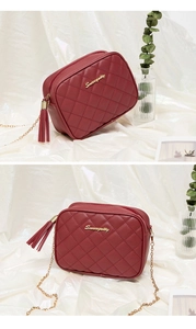 Macro shot of quilted burgundy camera bag with gold logo, leather tassel and chain