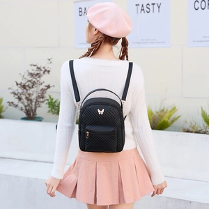 Minimalist black quilted mini backpack with golden butterfly logo and V-shaped stitching