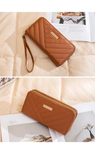 Close-up of brown quilted long wallet with double zippers and elegant wrist strap detail