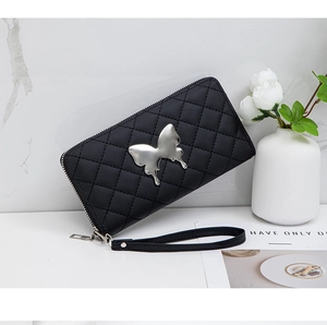 Detailed shot of black quilted wallet featuring a metallic silver butterfly and wrist strap