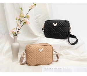 Detail of quilted crossbody bags with butterfly clasps in black and cream beige