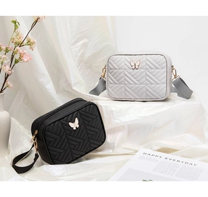 Detail of quilted butterfly crossbody bags in black and grey with woven shoulder straps