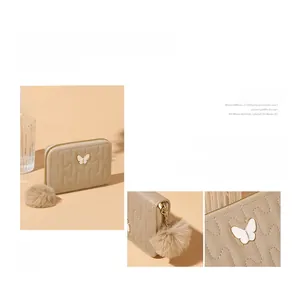Detail of beige quilted faux leather wallet with butterfly ornament and plush pompom charm