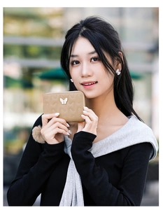 Detail of khaki quilted short wallet for women featuring metal butterfly and pom pom charm