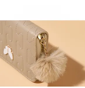 Close-up of light brown PU leather wallet with wave stitching and fuzzy ball charm
