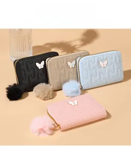 Quilted heart wallets with golden butterfly charms and plush pompom details