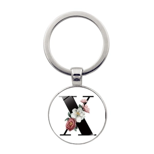Détail d'un porte-clés argenté avec lettre X florale et anneau métallique poli