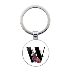 Détail d'un pendentif porte-clés rond avec lettre W fleurie et anneau en métal argenté