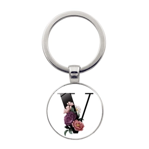 Gros plan d'un porte-clés en métal argenté avec motif floral de la lettre V