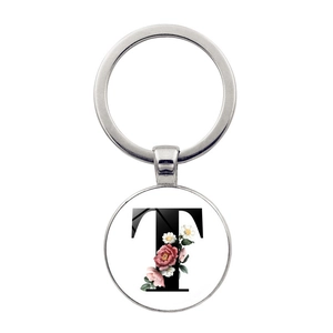 Détail du porte-clés argenté avec lettre T et motif floral sous dôme en verre poli