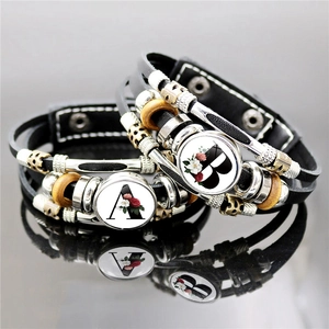Detail of layered leather bracelets with letter A and B glass pendants and rose motifs