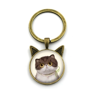 Detalle de llavero de bronce con orejas de gato e ilustración de gatito de pelo corto