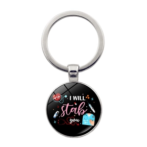 Macro shot of circular medical keychain with I Will Stab You text and stethoscope detail