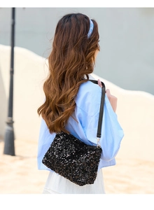Detail shot of a black sequin baguette bag worn as an underarm shoulder bag for daily style