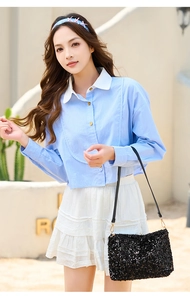 Detail of a black sequin shoulder bag paired with a light blue striped long sleeve shirt