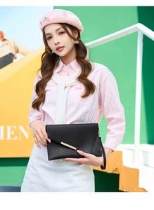 Dettaglio dell'elegante pochette a busta nera con finiture dorate e cinturino a mano