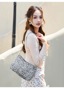 Detail of silver sequin baguette bag with gold metal hook and slim grey strap
