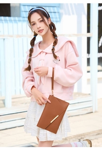 Dettaglio di una pochette in pelle marrone con barra metallica dorata e cinturino da polso