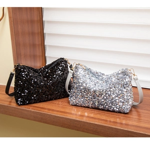 Close-up of black and silver sequined handbags with metallic zippers on a wooden table