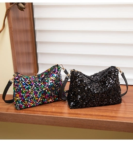 Detail of colorful and black sequin shoulder bags with golden hooks on a wood table
