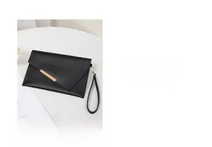 Dettaglio della pochette a busta in pelle nera martellata con barra dorata e cinturino