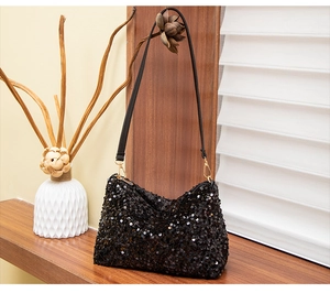 Detail of black sequined shoulder bag with gold metal buckle on a wooden surface